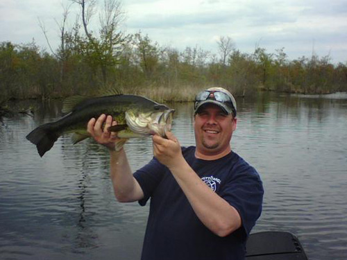 Man in blue shirt holding large bass