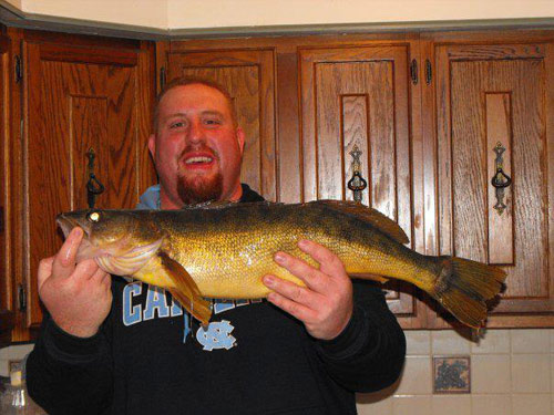 Man holding large fish in his kitchen