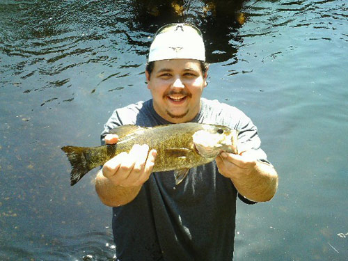 Smiling man in lake holding a fish
