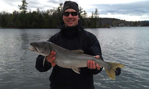 Man in cold-weather gear holding large salmon