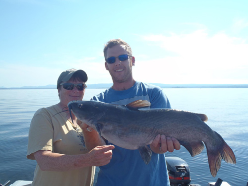 A couple in a boat holding a large fish