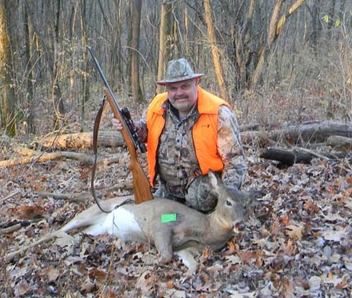 Hunter in bright orange vest with white-tailed deer he shot