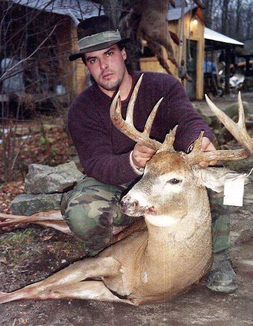 Hunter in purple sweater holding up head of a 10-point buck