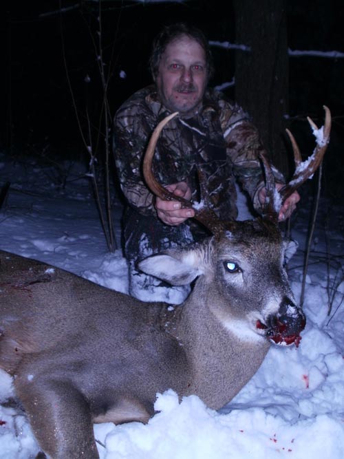 Hunter in snow with large white-tailed deer