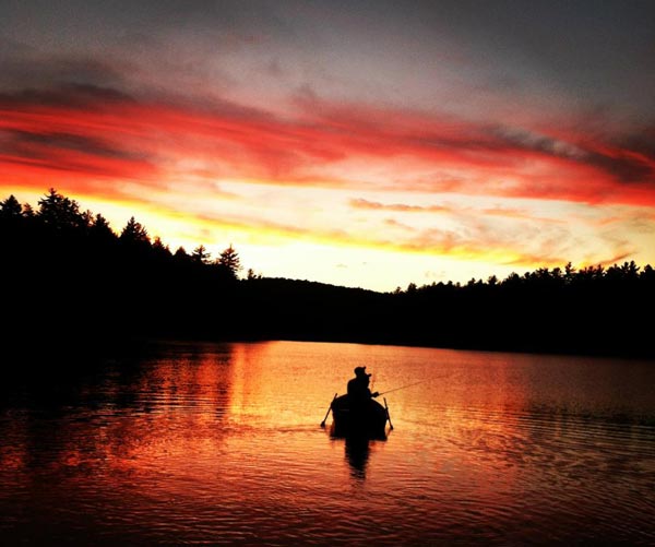 silhouette fishermen on a pond at sunset