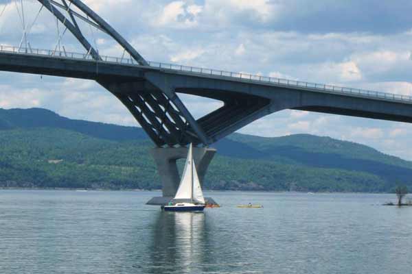 sailboat in front of a bridge