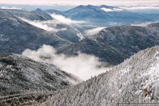 Snow covered mountain peaks with low cliuds in the valleys