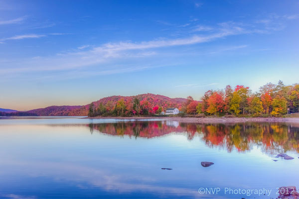 Still lake lined by brilliant red fall foliage