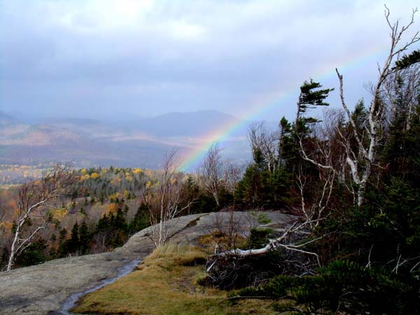 a rainbow at the summit of a mountain