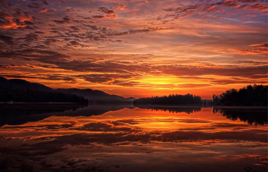 sun rising over alger island on fourth lake