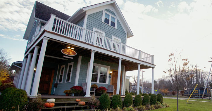 a light blue bed and breakfast with pumpkins on the porch