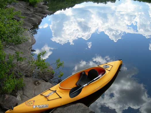 a yellow kayak on the edge of very still, reflective waters