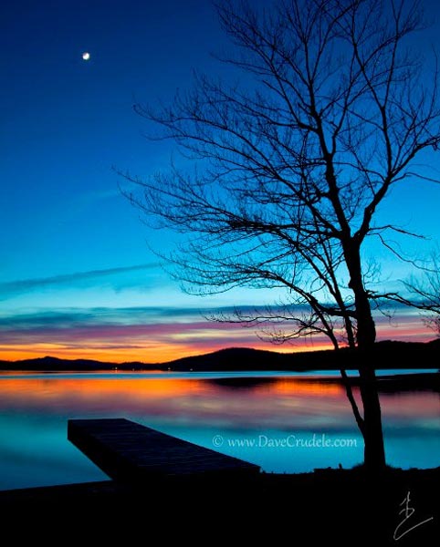 Tree and boatlaunch over a lake at sunset