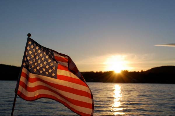 American flag against the sunset over a lake