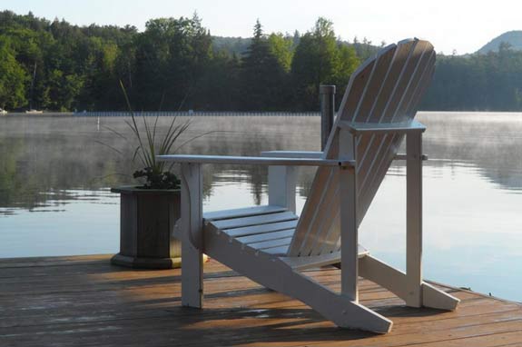 white adirondack chair on a dock overlooking water