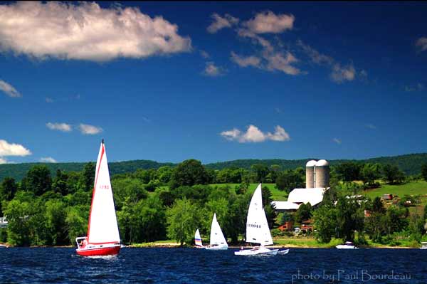 Sailboats on Great Sacandaga Lake in front of a lakeshore farm