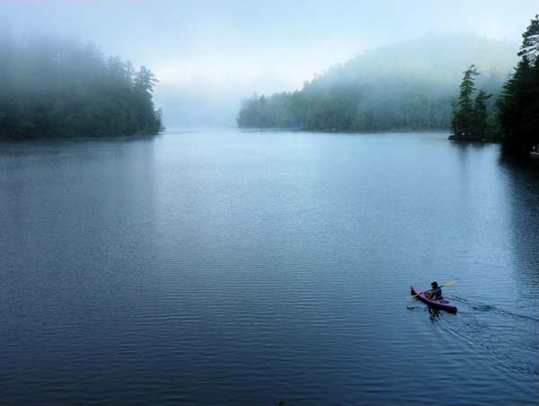 lone kayaker paddles on a foggy lake