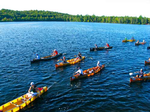 a group of canoes paddling along a lake