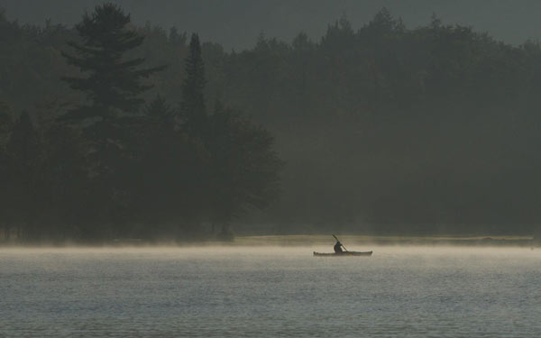 Lone kayaker paddling on a foggy morning