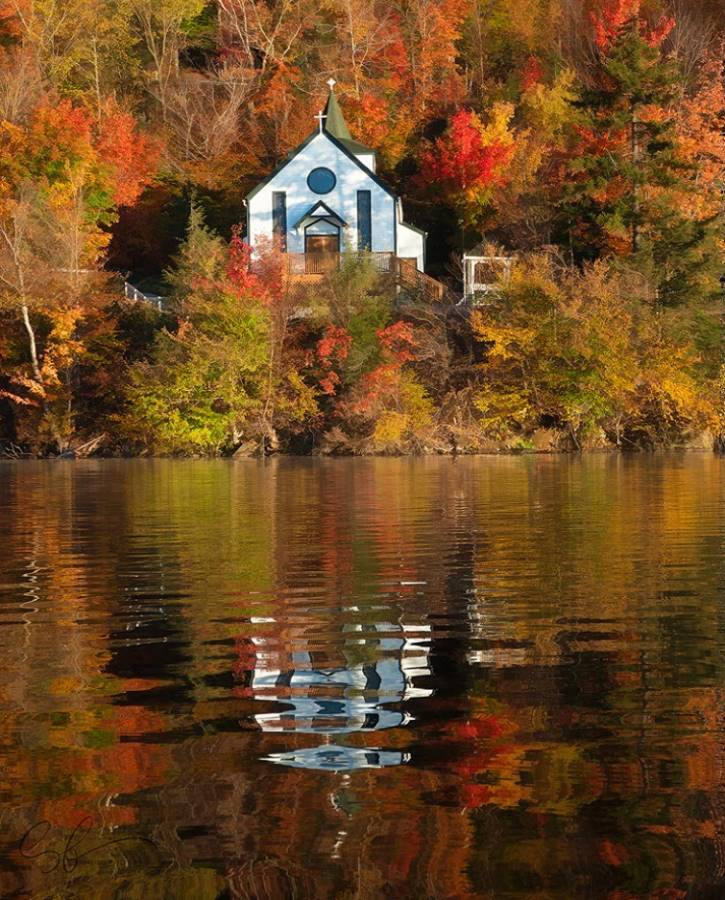 Small chapel on a lake surrounded by fall foliage