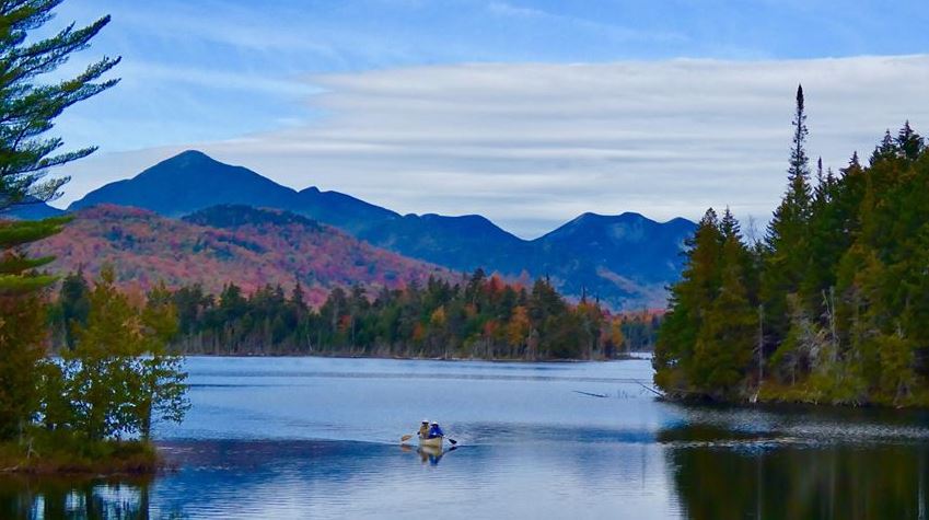 Canoe on a pond with fall foliage and mountains