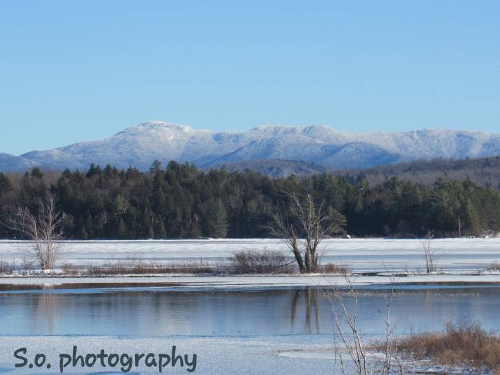 Partially frozen lake with snowy mountains