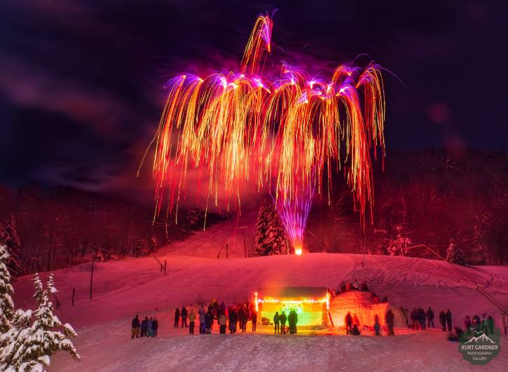 Pink & orange fireworks over igloo with bystanders