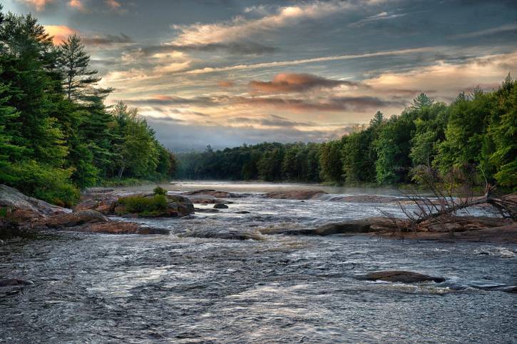 Blue & orange sunrise over river lined with trees