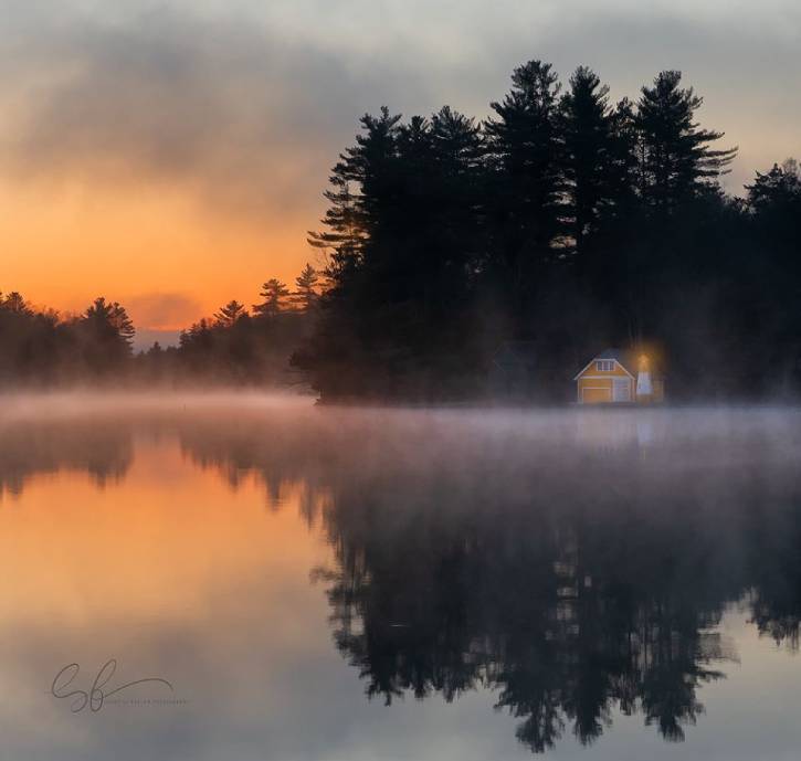 Orange sunrise over a pond with fog & yellow house