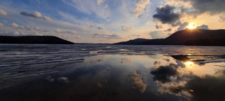 Blue and orange sunset reflected on lake with ice