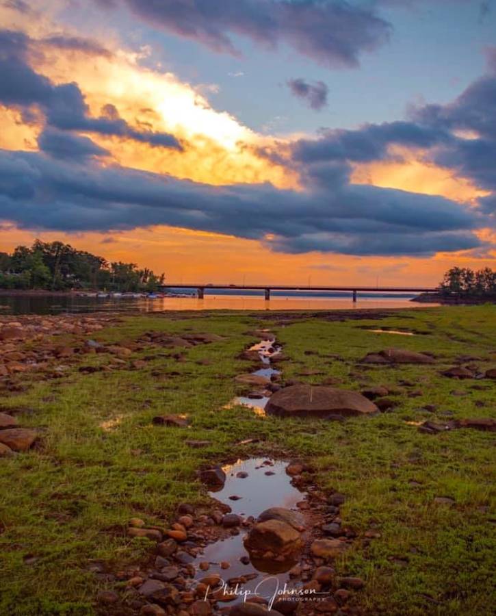 Blue and orange sunset over water and muddy grass