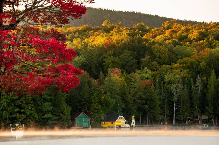 Foggy lake with fall foliage and yellow boathouse