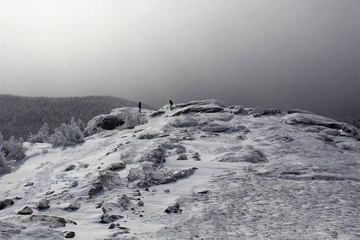 two people on a mountain summit in winter