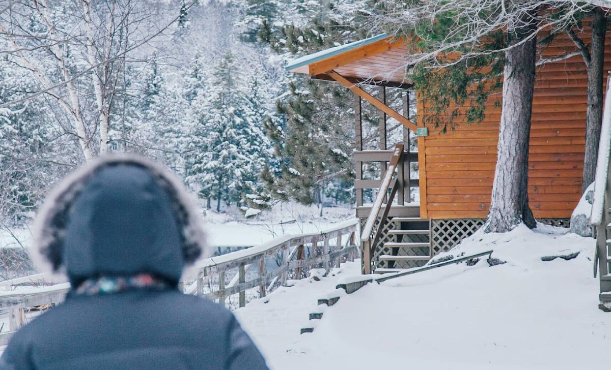 person in winter coat looking at cabin