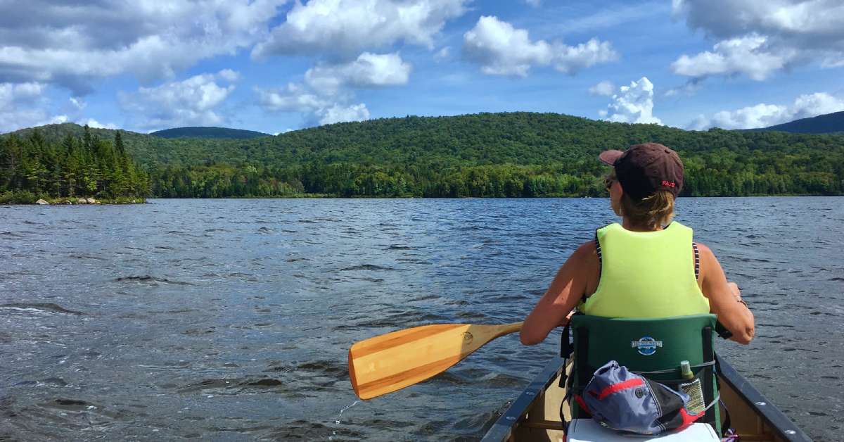 a woman canoeing on an adirondack lake