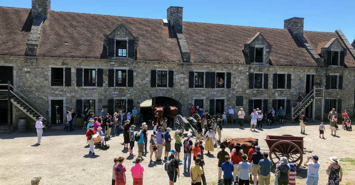 crowd outside a large stone building at fort ticonderoga