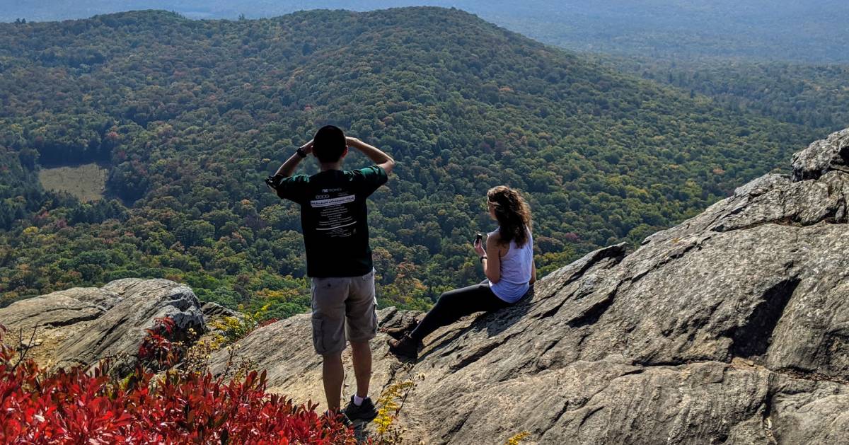 a man and woman on a mountain summit looking out