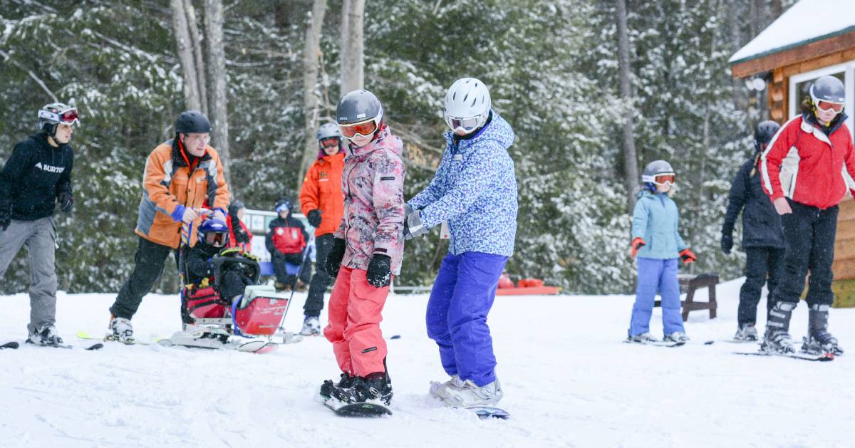 group of kids and adults about to ski down a mountain