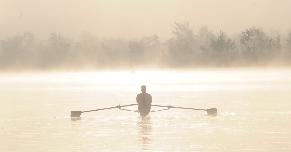 a person paddling on a misty lake