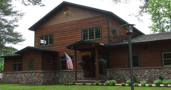 a large, Adirondack-style house with wood panneling and an American flag out front