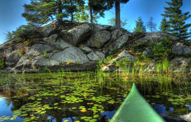 tip of green kayak on pond