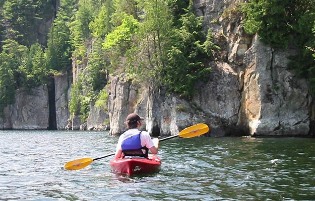 a kayaker near rocky cliff